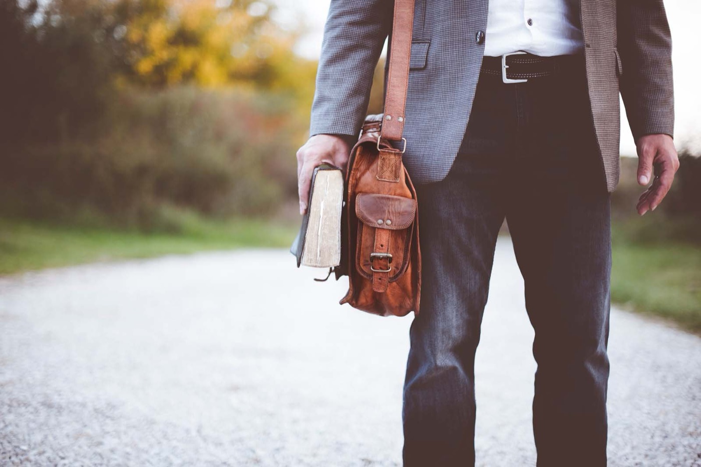 A pastor walking with a worn Bible and shoulder bag
