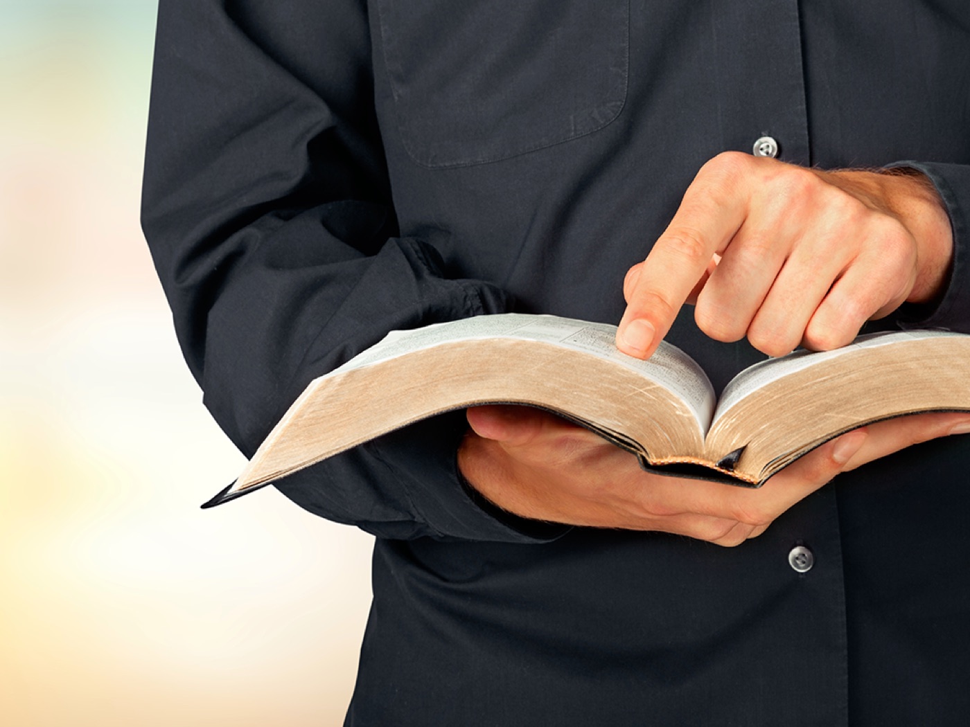 A man holding an open Bible and pointing to the page